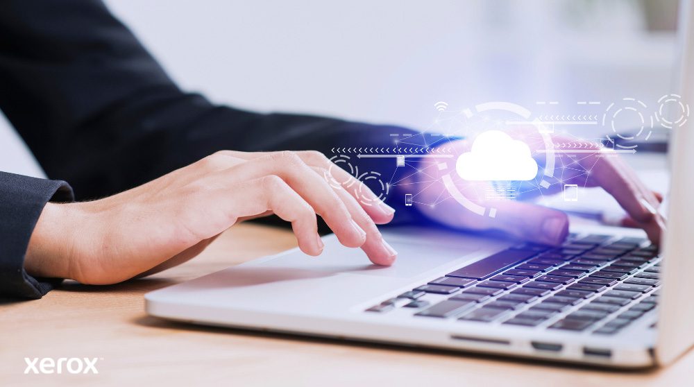 Xerox® Workplace Cloud et Suite : connectivité cloud Les mains d'une personne sont représentées en train de taper sur un clavier d'ordinateur portable, avec une icône de nuage lumineux et des connexions réseau superposées sur l'image, symbolisant la connectivité cloud et les flux de travail numériques.